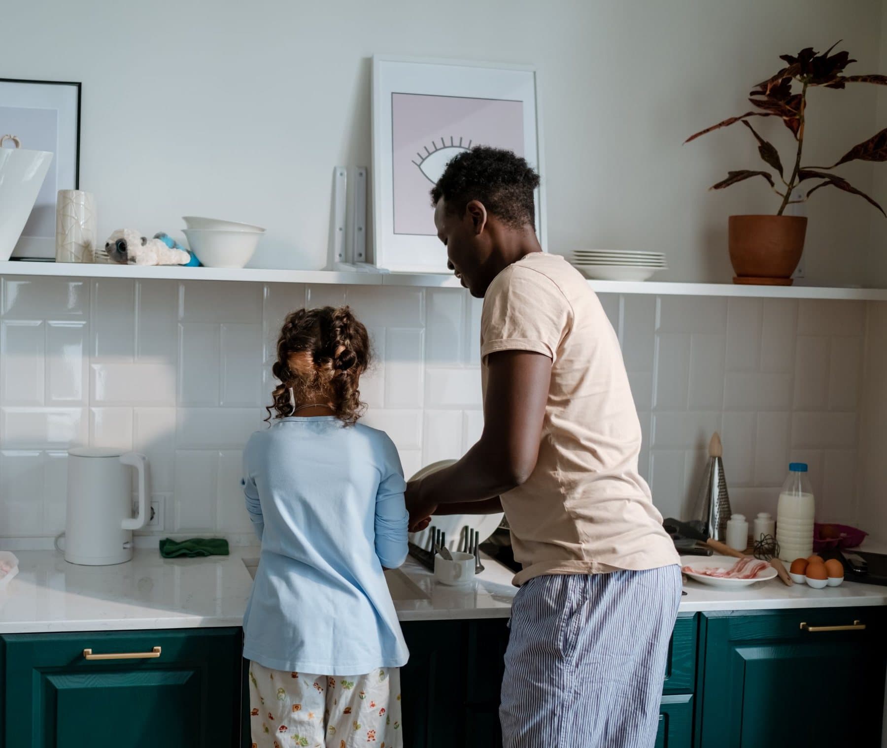 A father and his daughter washing up together at a kitchen sink