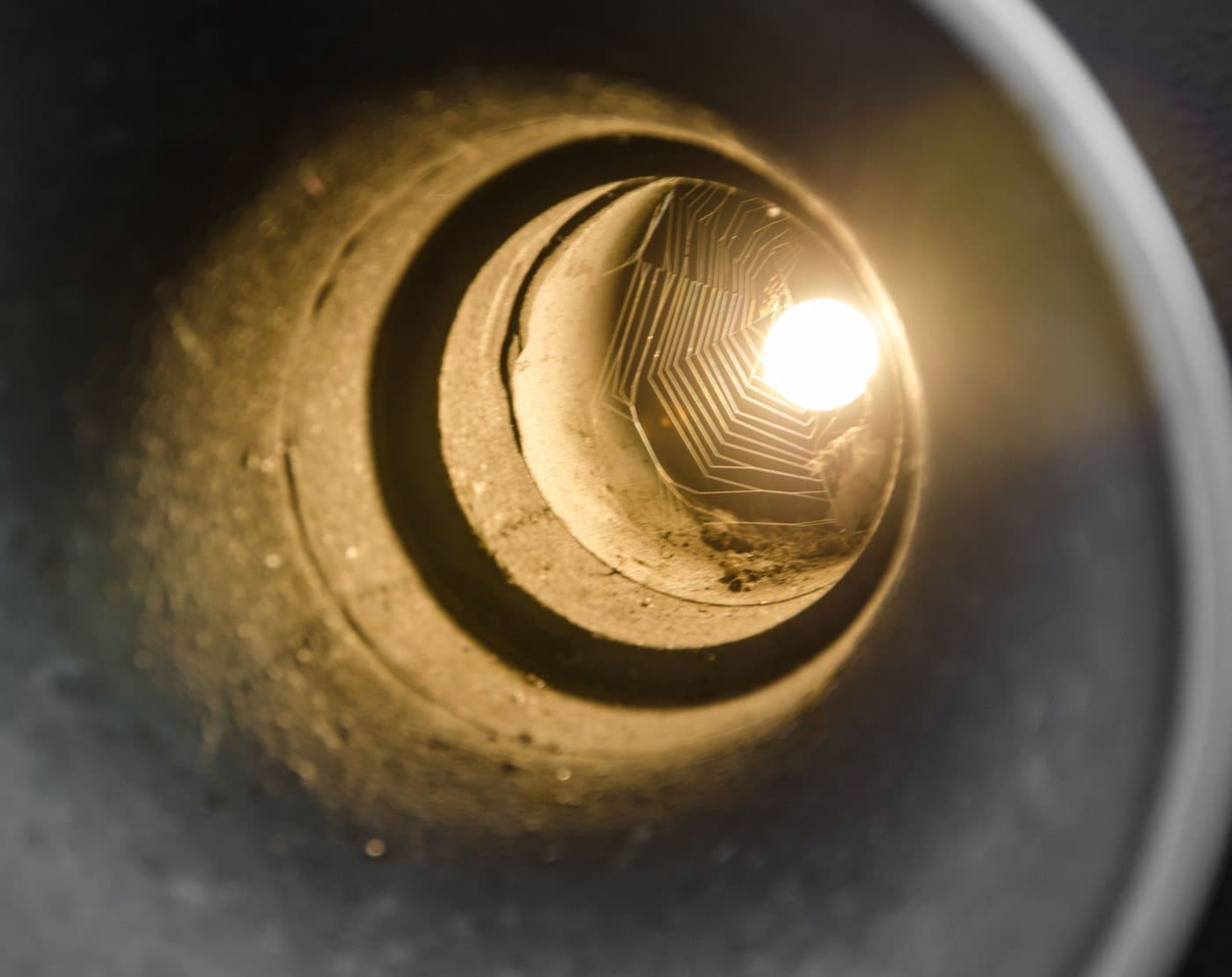 Looking down the inside of a round pipe toward a light at the far end