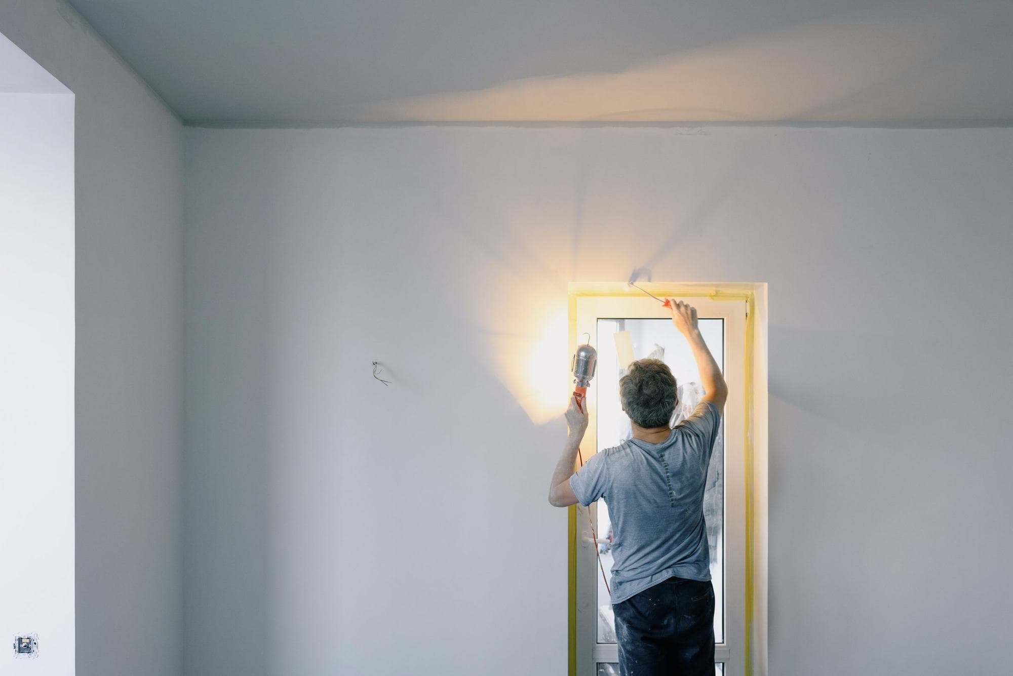 A handyman working a lit door frame in a freshly painted room