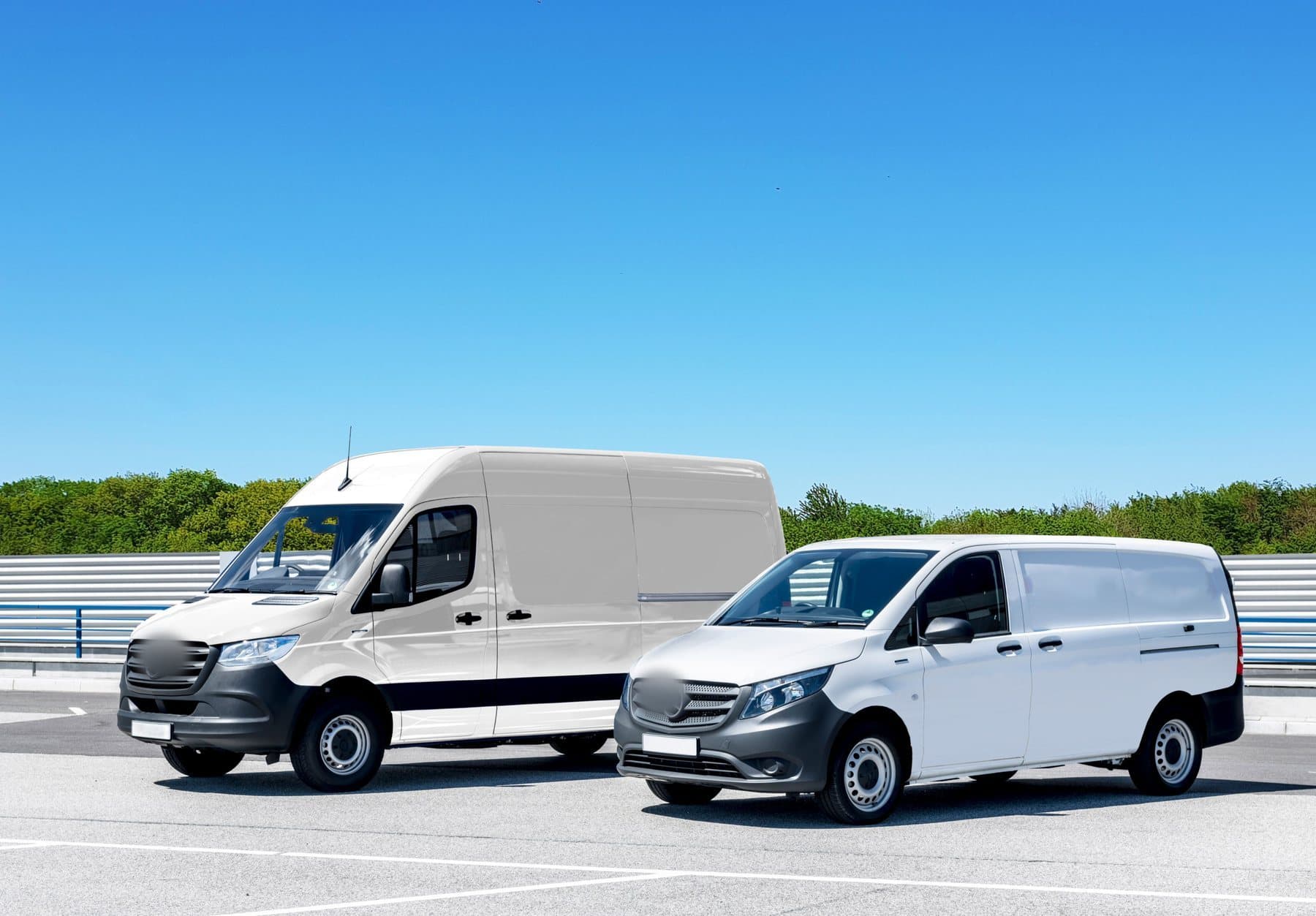 Two clean white work vans parked side by side on an open lot under a blue sky