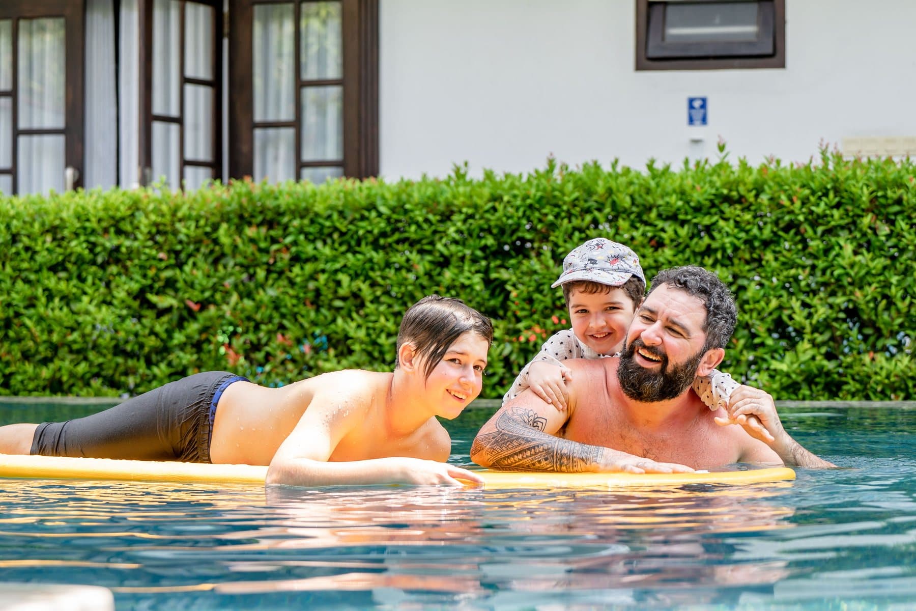 A father and two children on a float in a clear backyard pool. A photo from Sandhill Pool Service, the sample pool service website.