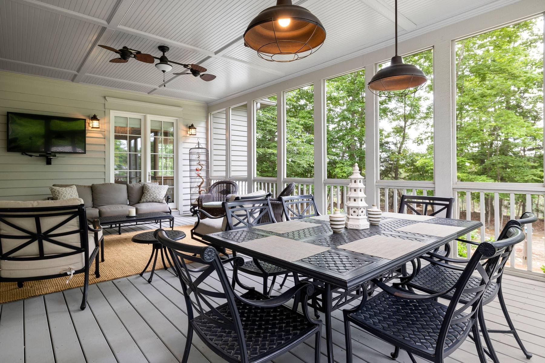 A screened porch set up for dinner, a table and chairs, woods beyond the screen. A photo from Latitude Screen & Rail, the sample screen enclosure website.