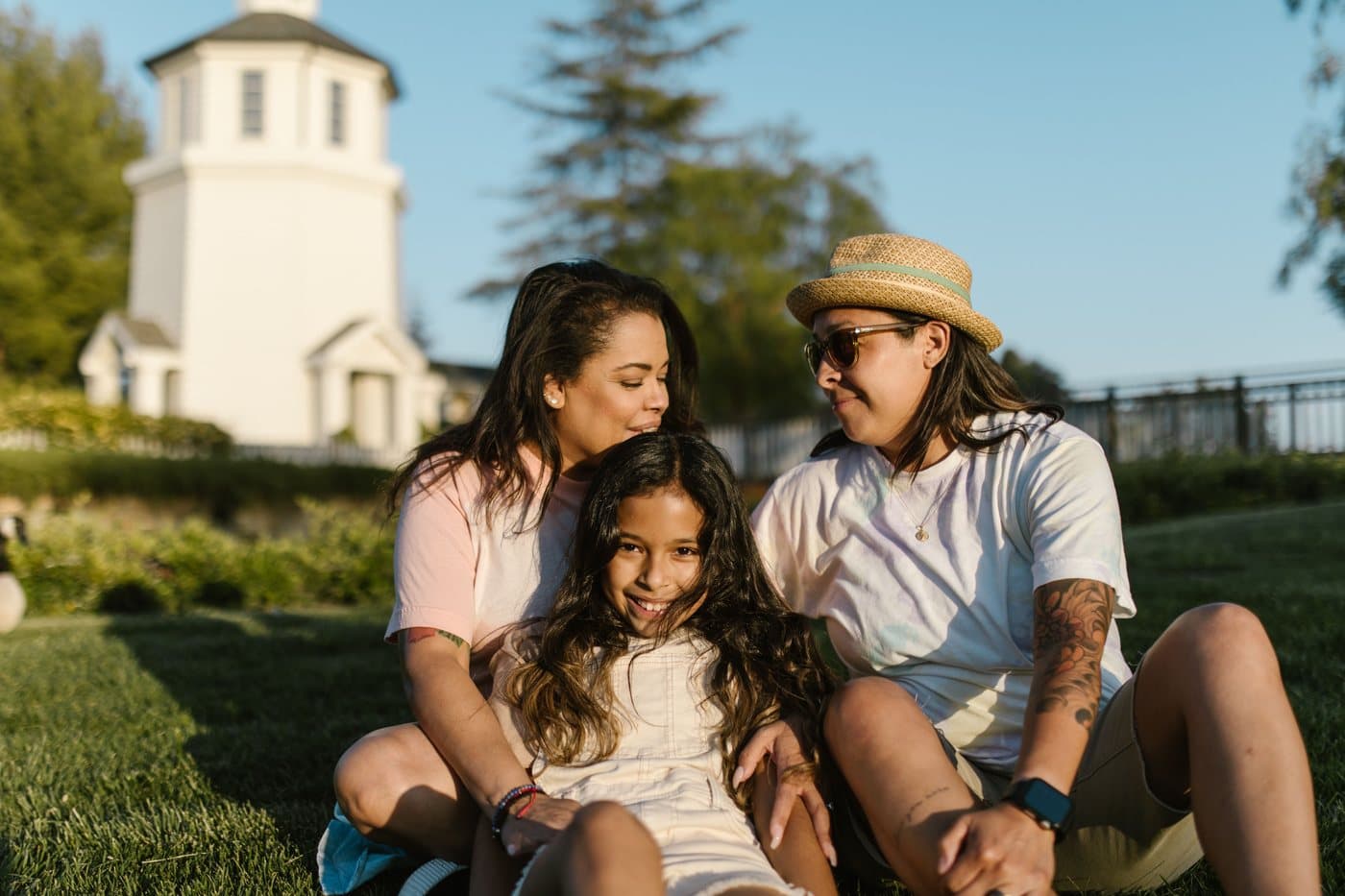 A family on a mown lawn Two women and a smiling girl sitting close together on a mown lawn in the late sun