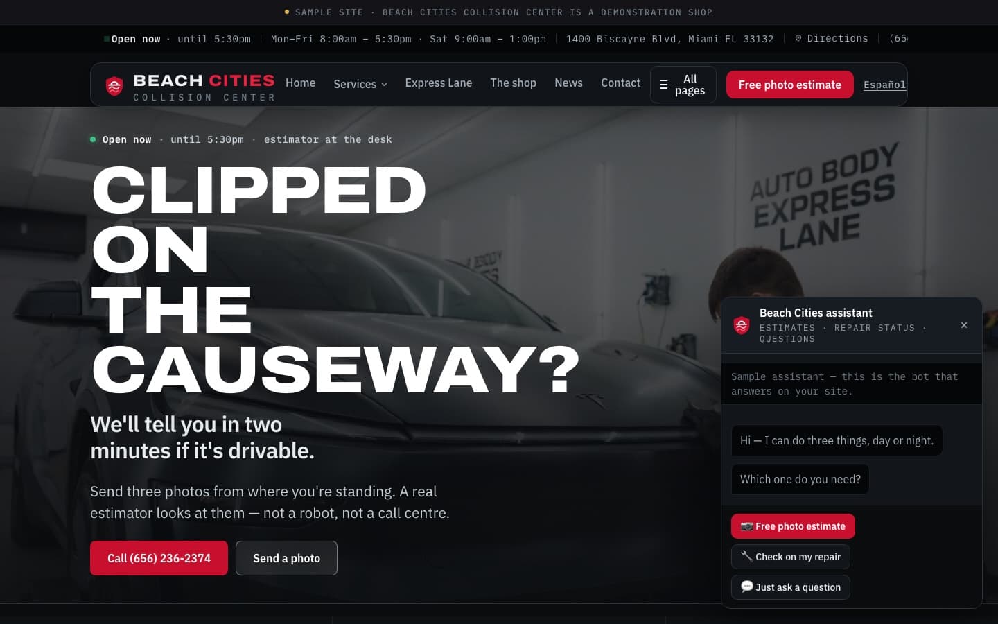 A finished shop website on a wide screen: a sample-site banner across the top, the shop's hours, address and phone in a bar beneath it, a full-bleed photograph of a car in the bay behind a headline reading Clipped on the causeway, and the site's own assistant open in the lower right offering a free photo estimate, a repair-status check, or a plain question.