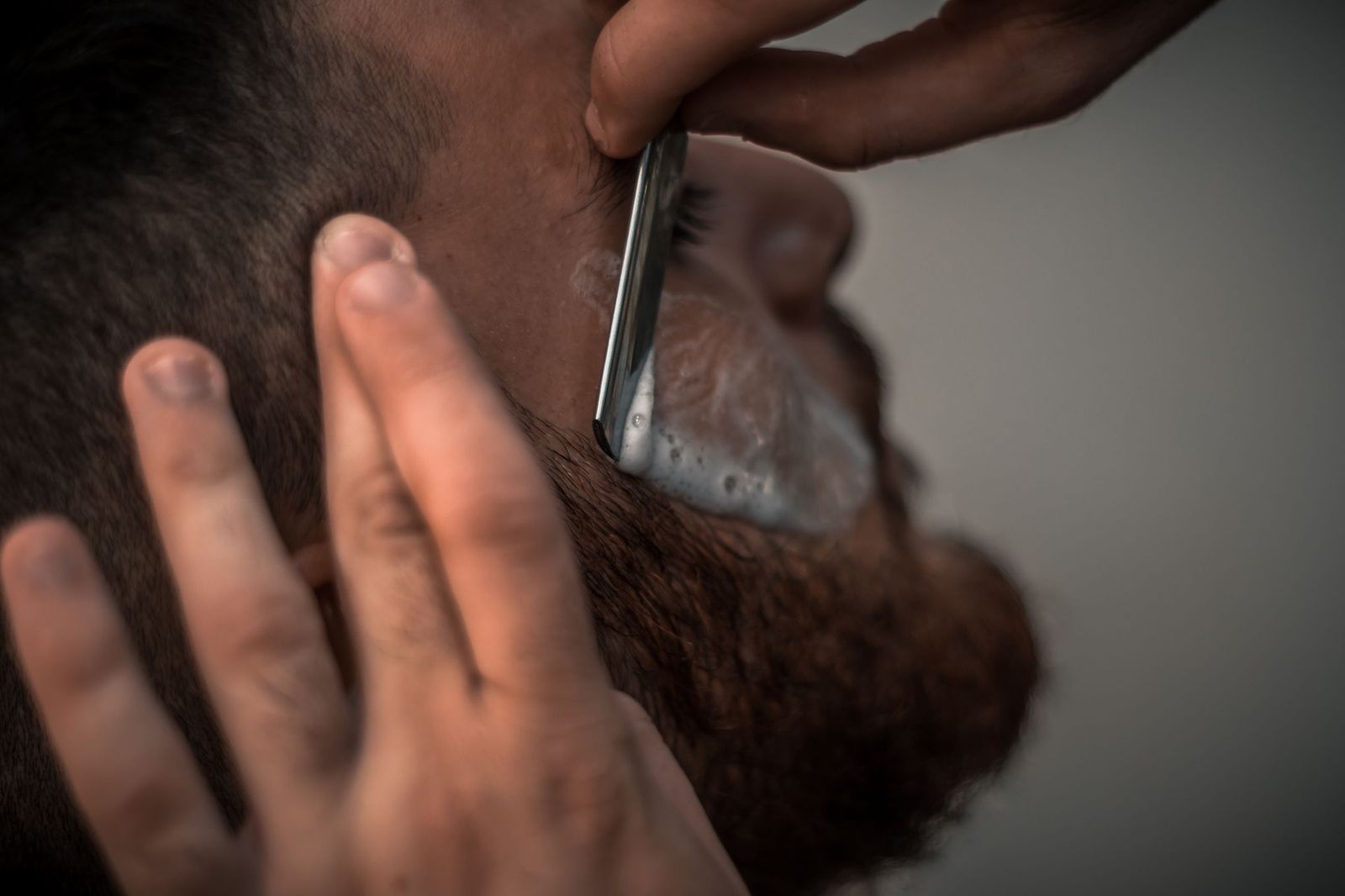 A straight razor cleaning up the edge of a beard along the cheek