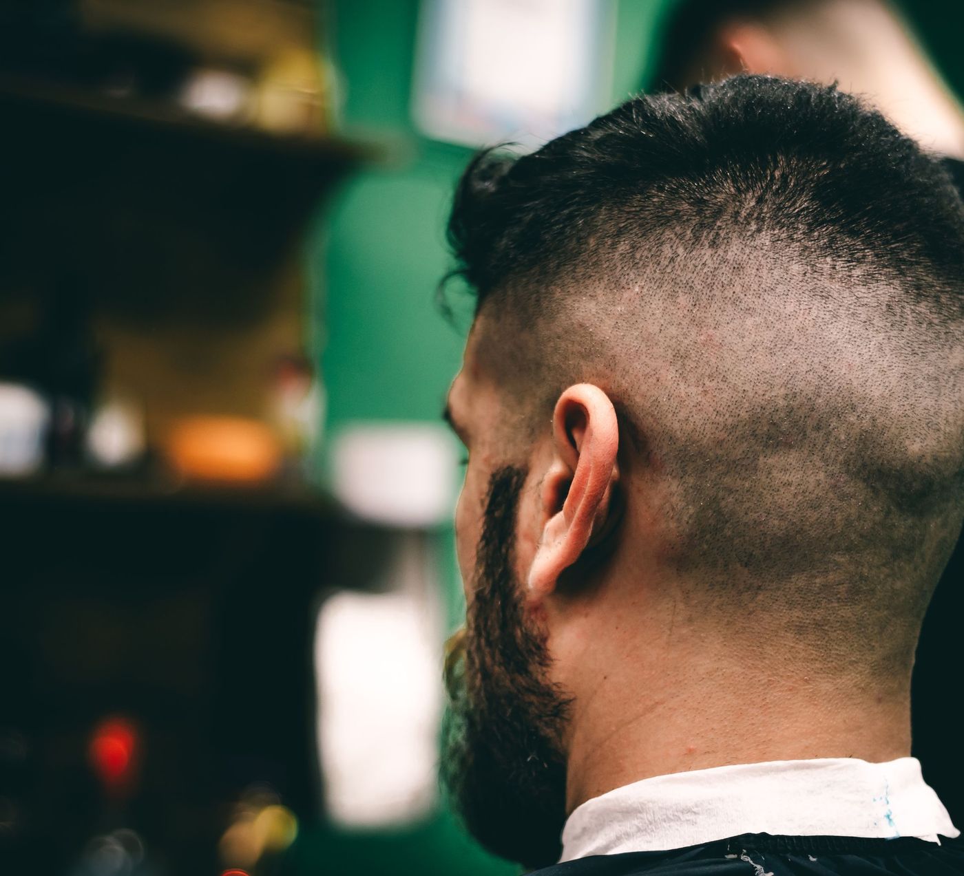 A high fade blended into a full beard, seen from behind