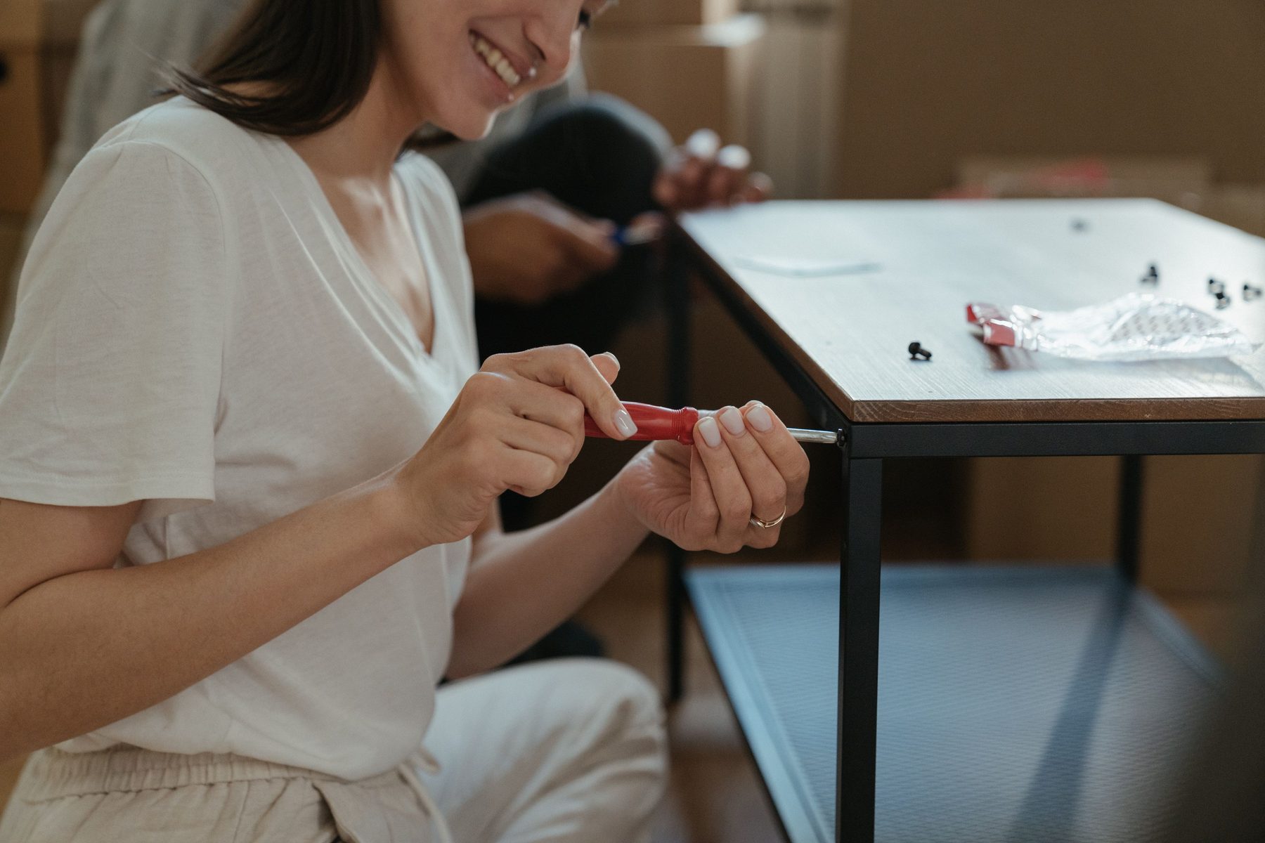 A smiling woman tightening a screw on a new side table