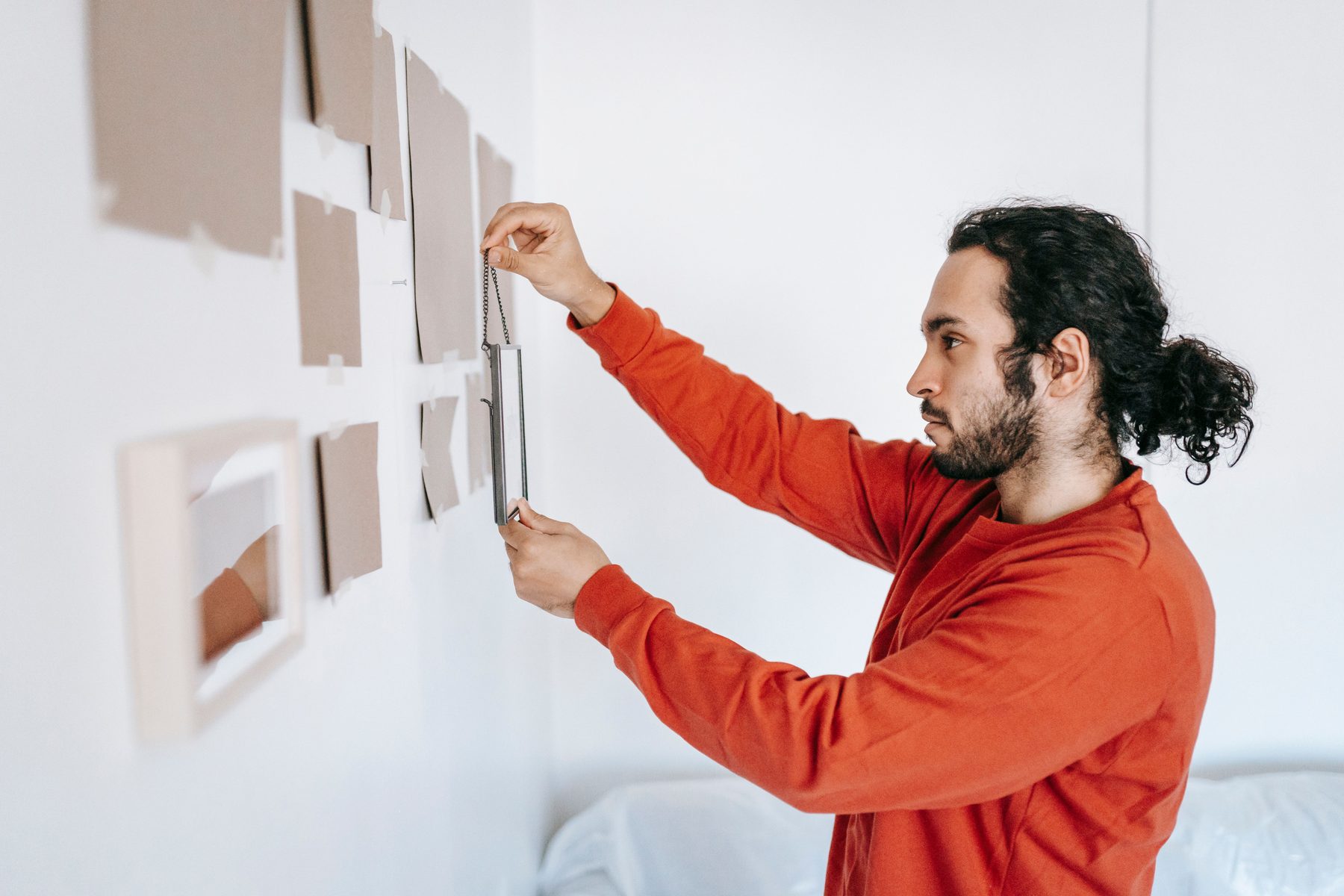 A man hanging frames for a gallery wall