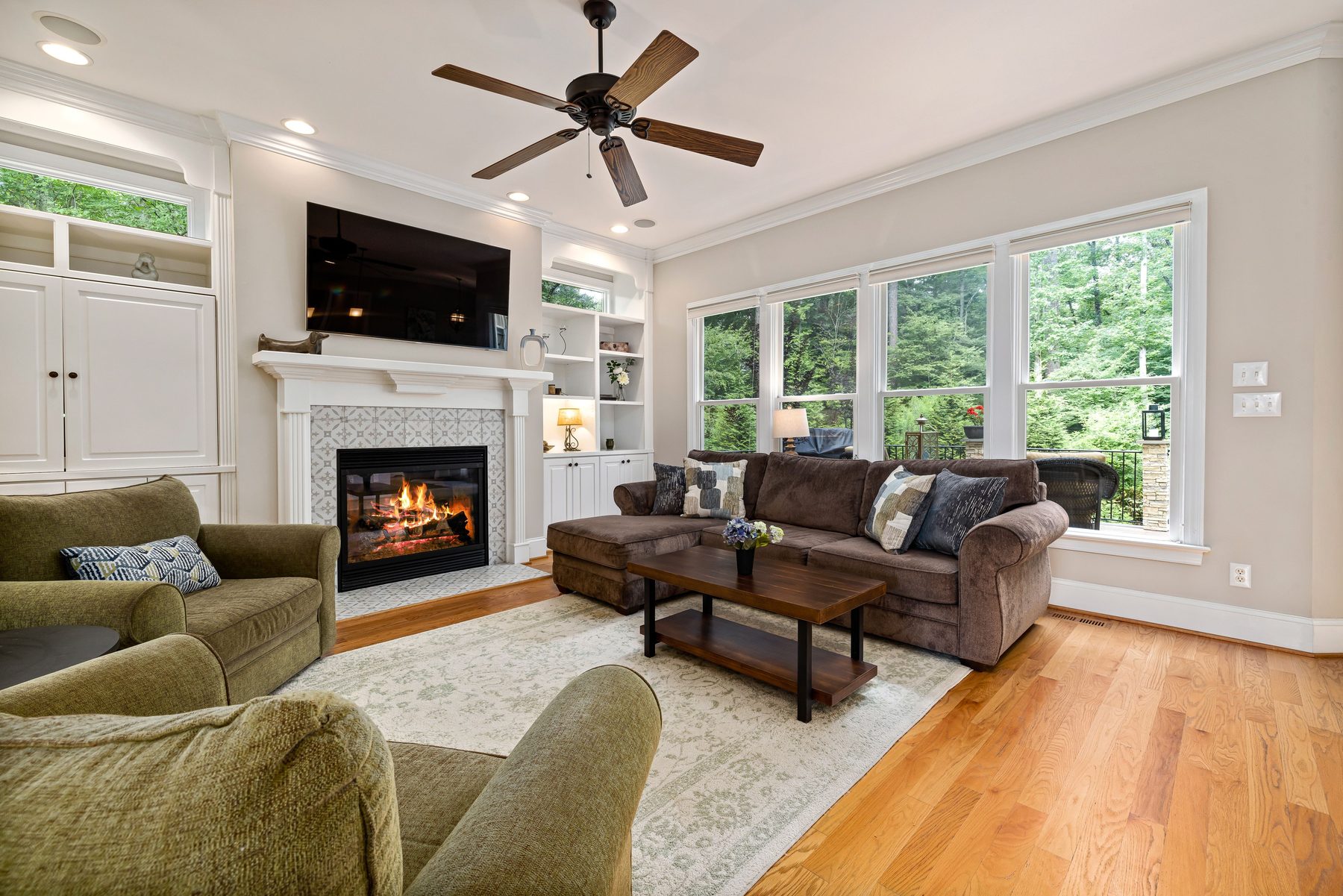 A finished family room with a wall-mounted TV above a fireplace and a sectional sofa