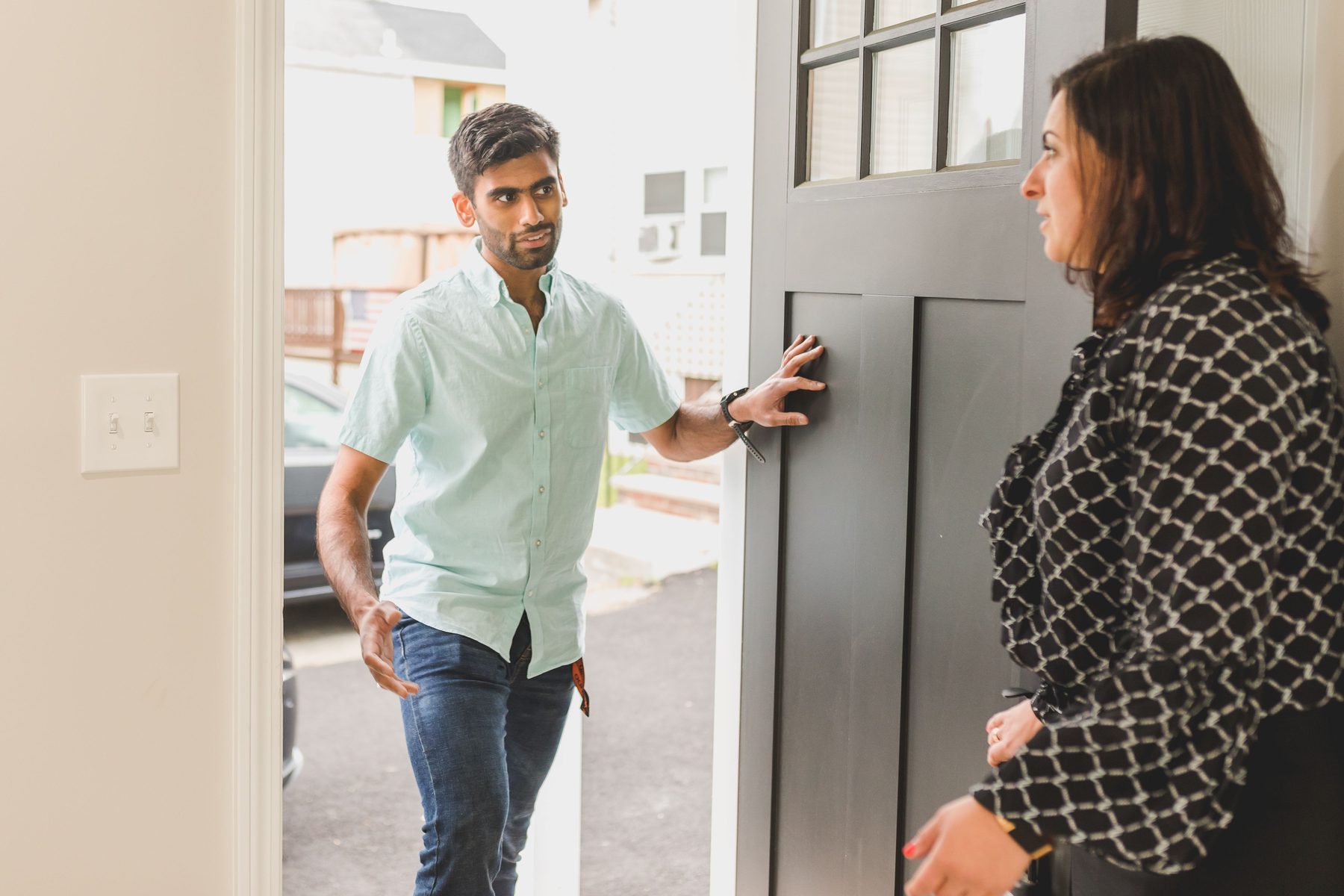A woman walking a young man in through the front door of a home