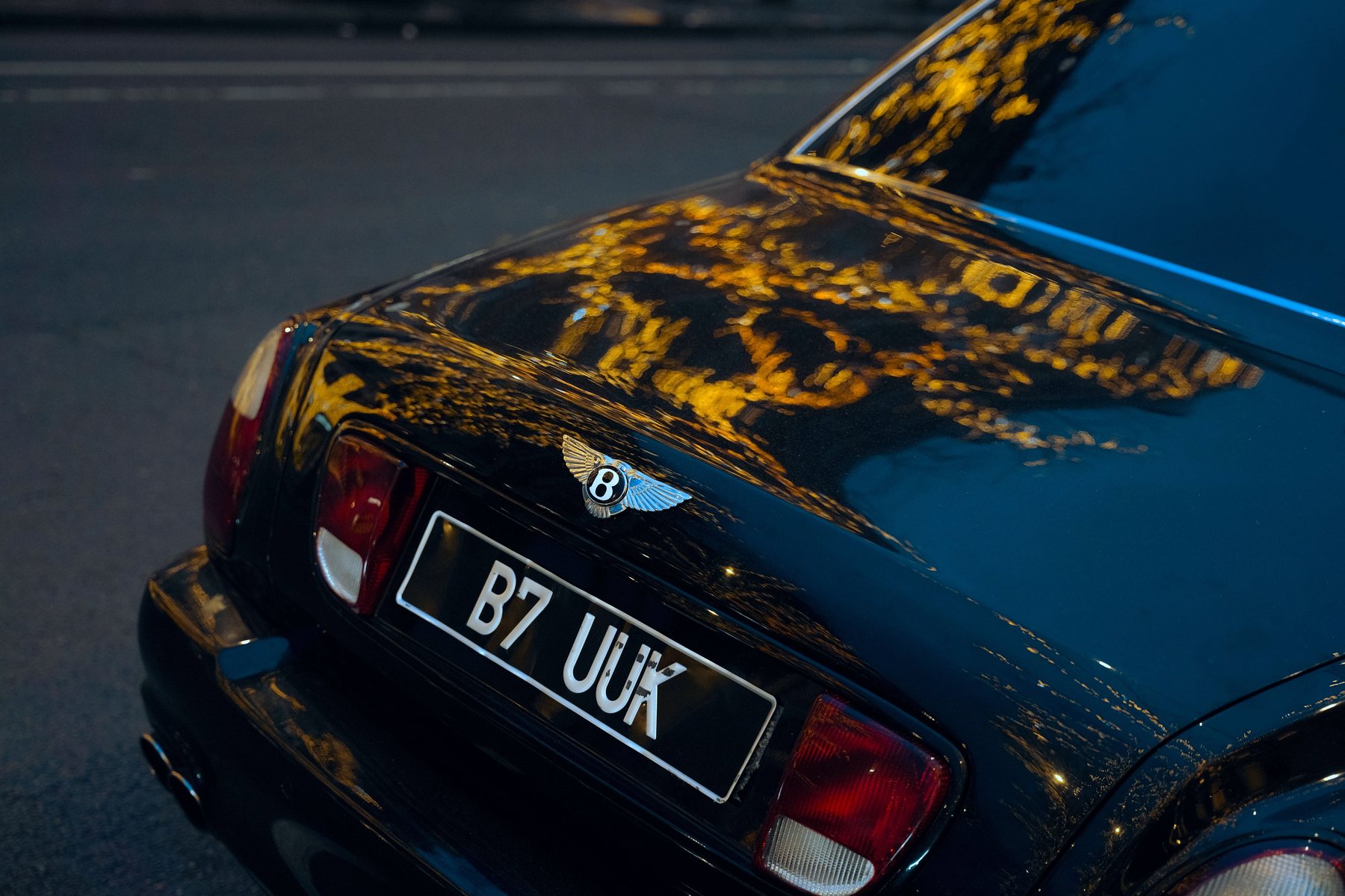 A dark car under lights, paintwork reflecting cleanly