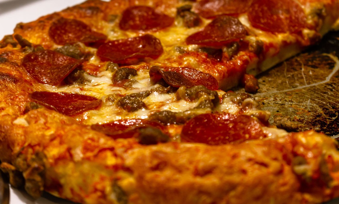 Close-up of a pepperoni and sausage pizza with crisp browned cheese and curled pepperoni edges