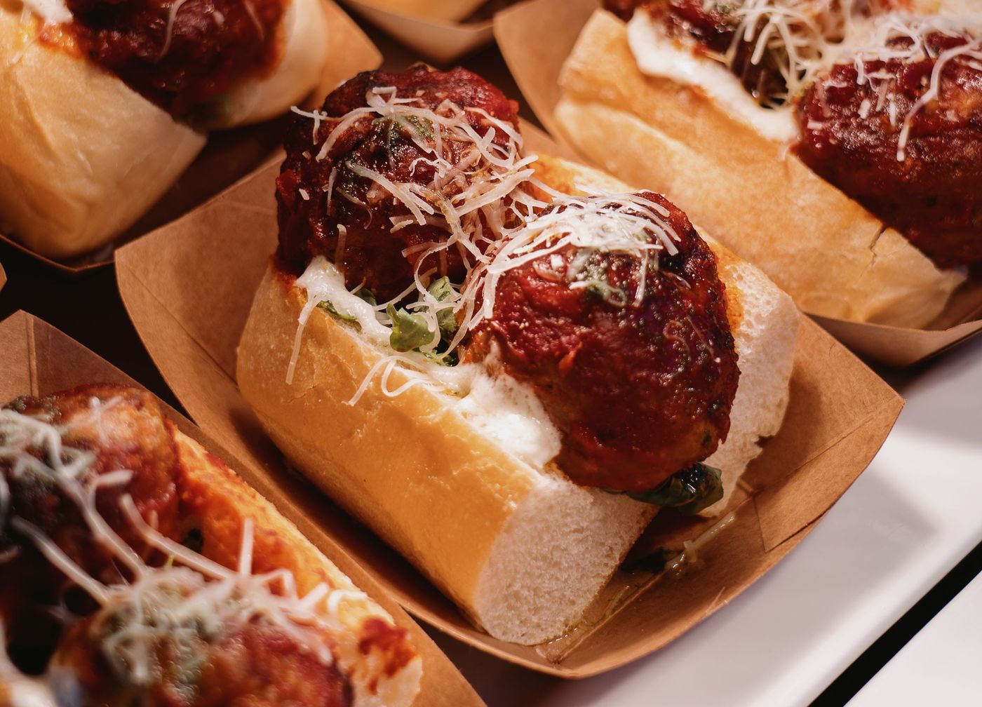 Meatball sub on a soft hero roll with marinara, melted mozzarella and grated parmesan, in a paper boat