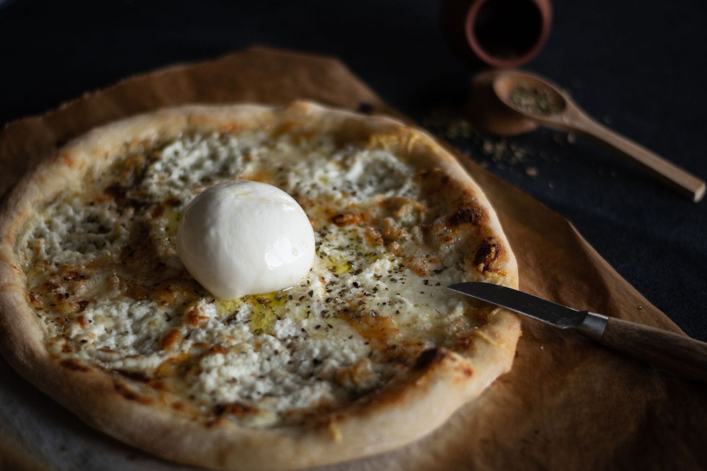 White pizza with ricotta, melted mozzarella, oregano and olive oil, topped with a ball of fresh burrata