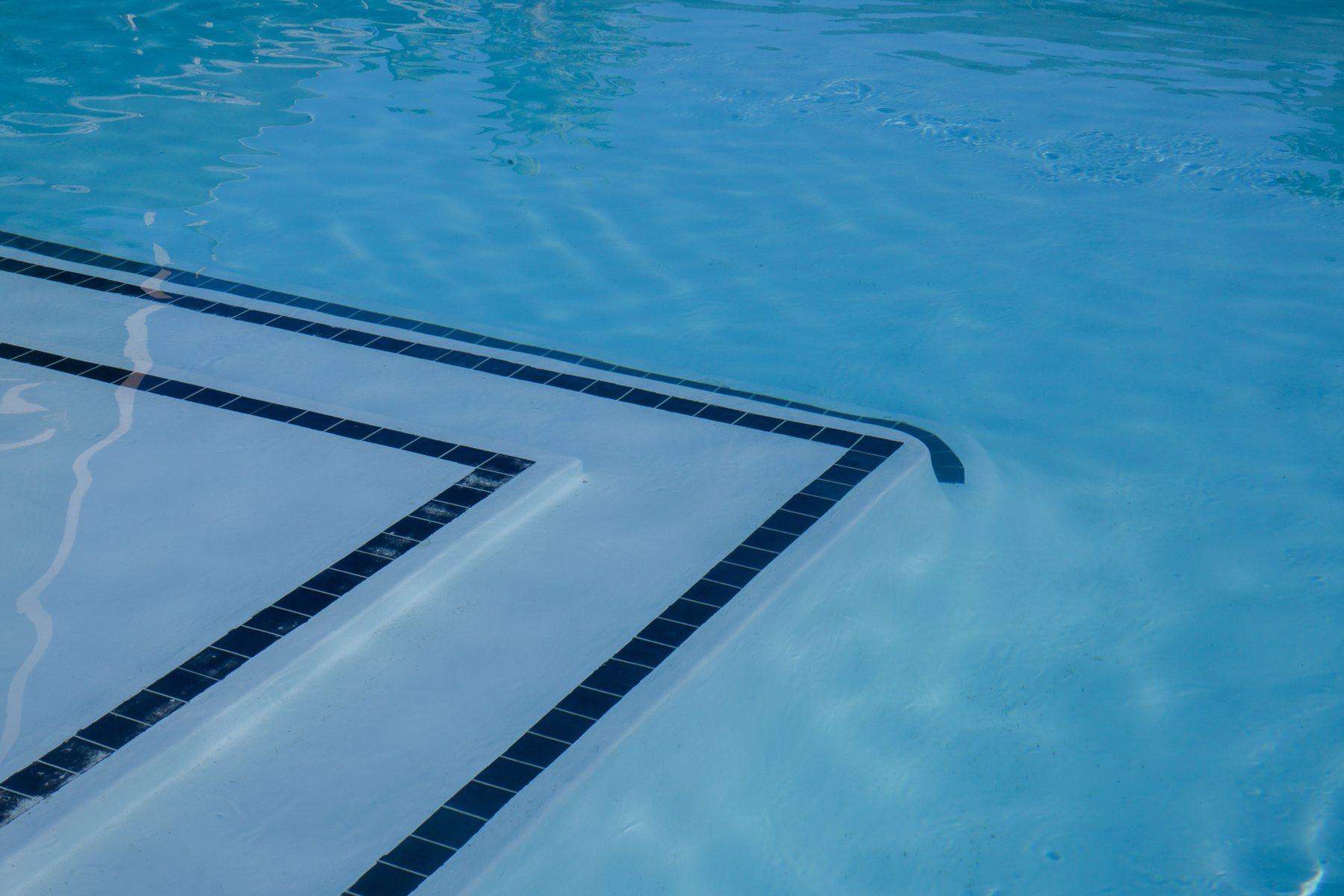 An empty pool shell with worn surface, cracks visible