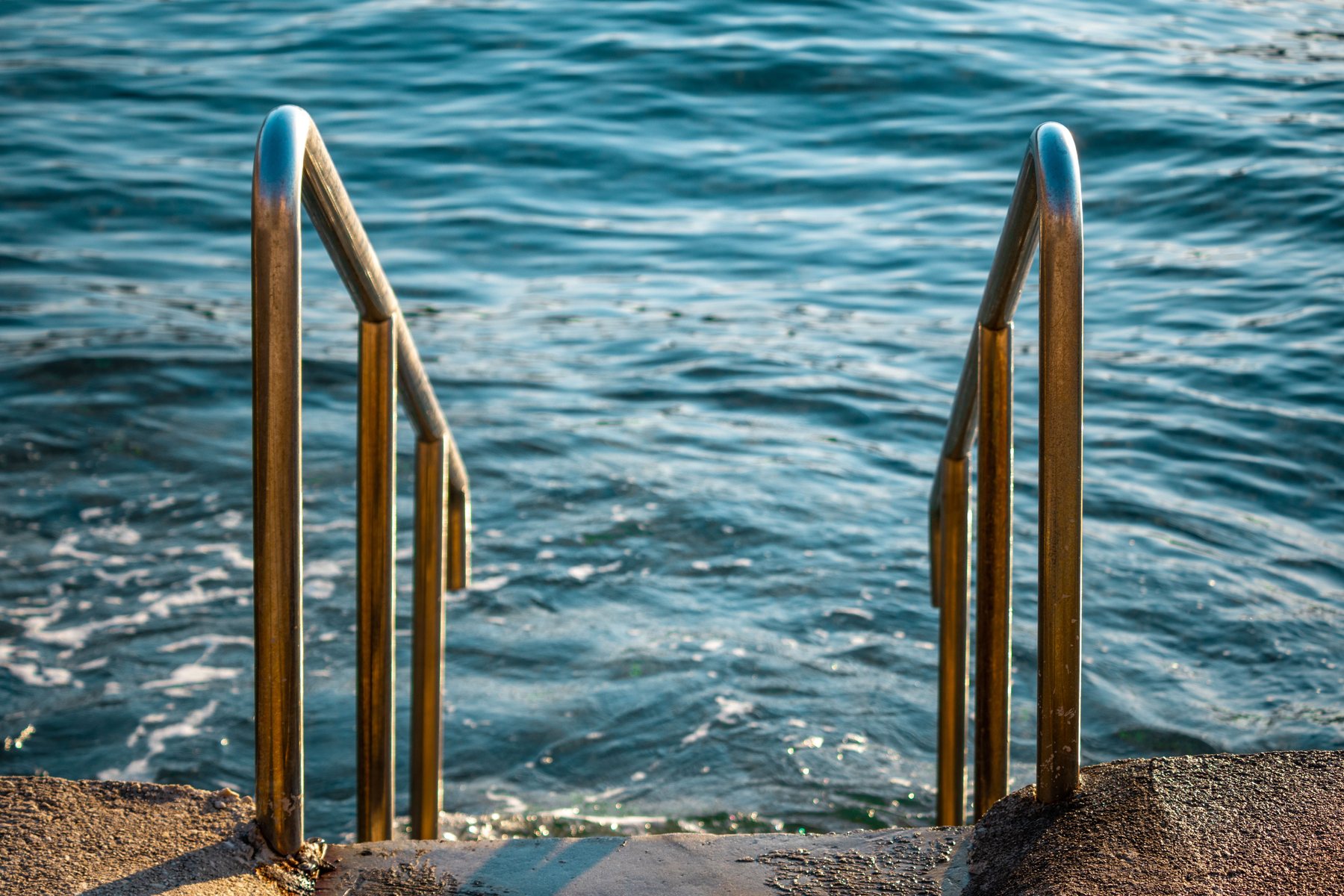 A pool ladder and handrail at the deck edge