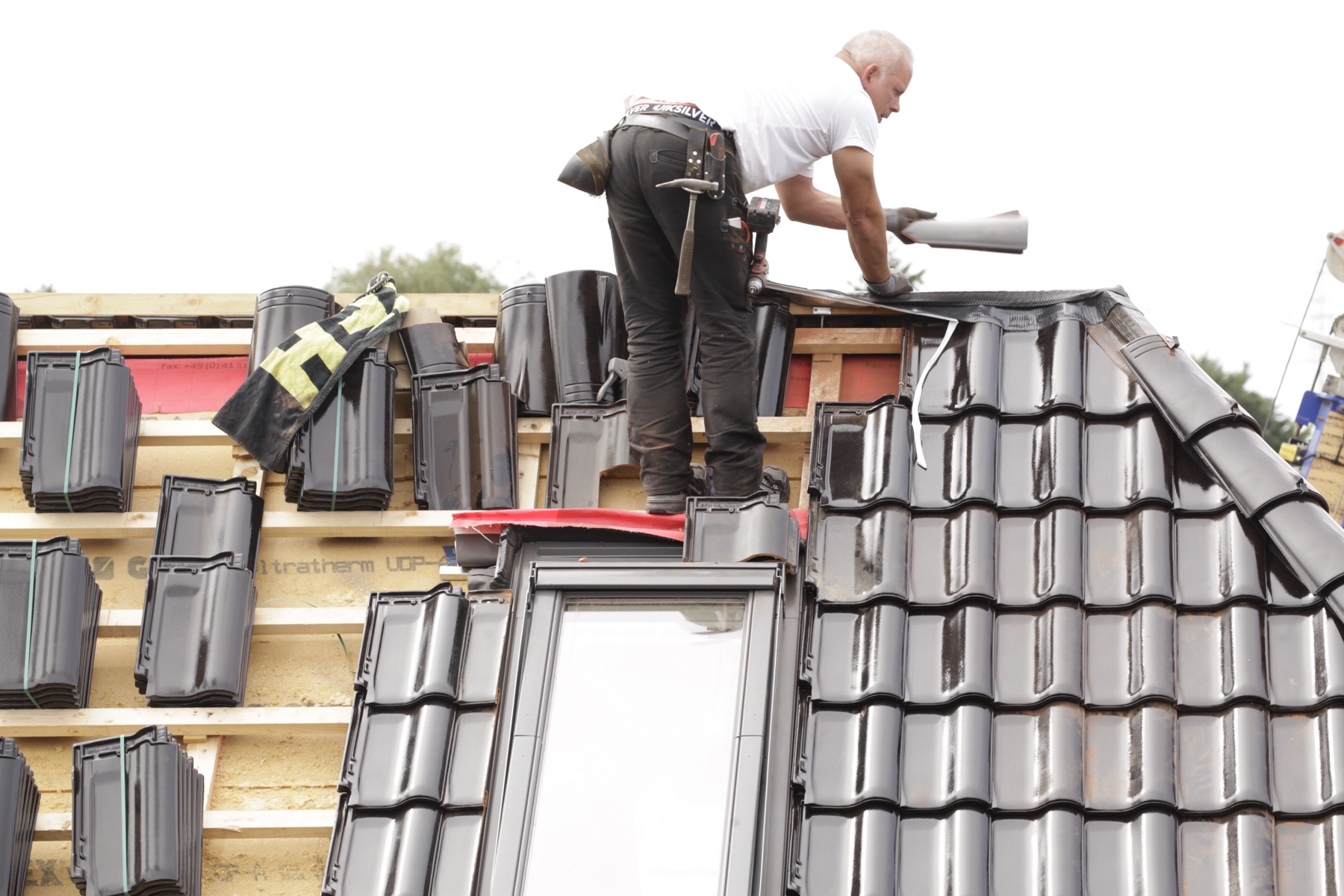 Tilers working their way up a tiled roof