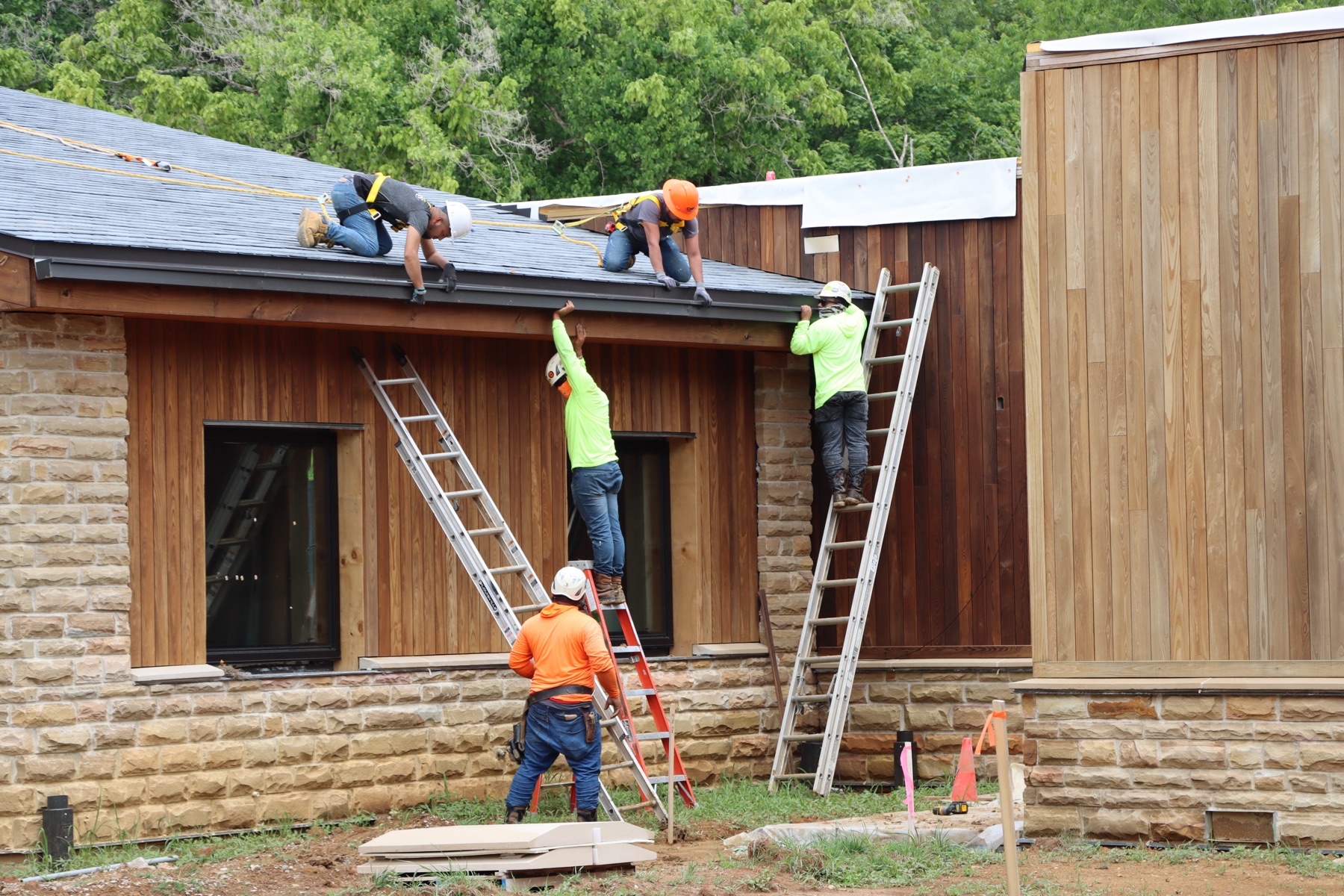 Gutter being installed along an eaves run from a ladder