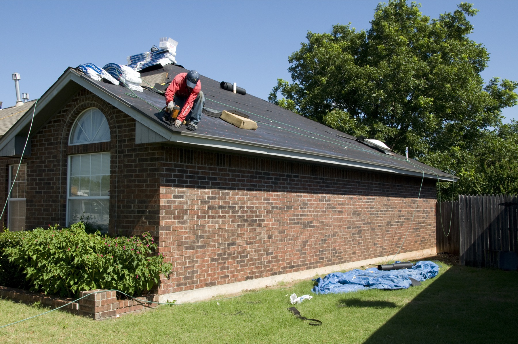 A roofer working across the slope of a house roof